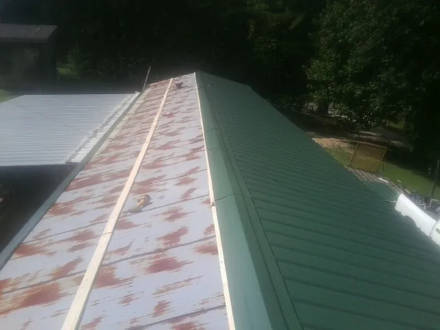 Old rusted panels beside newly installed green metal roofing — Wind Damage Roof Repair by Roofing Brothers in Oakland